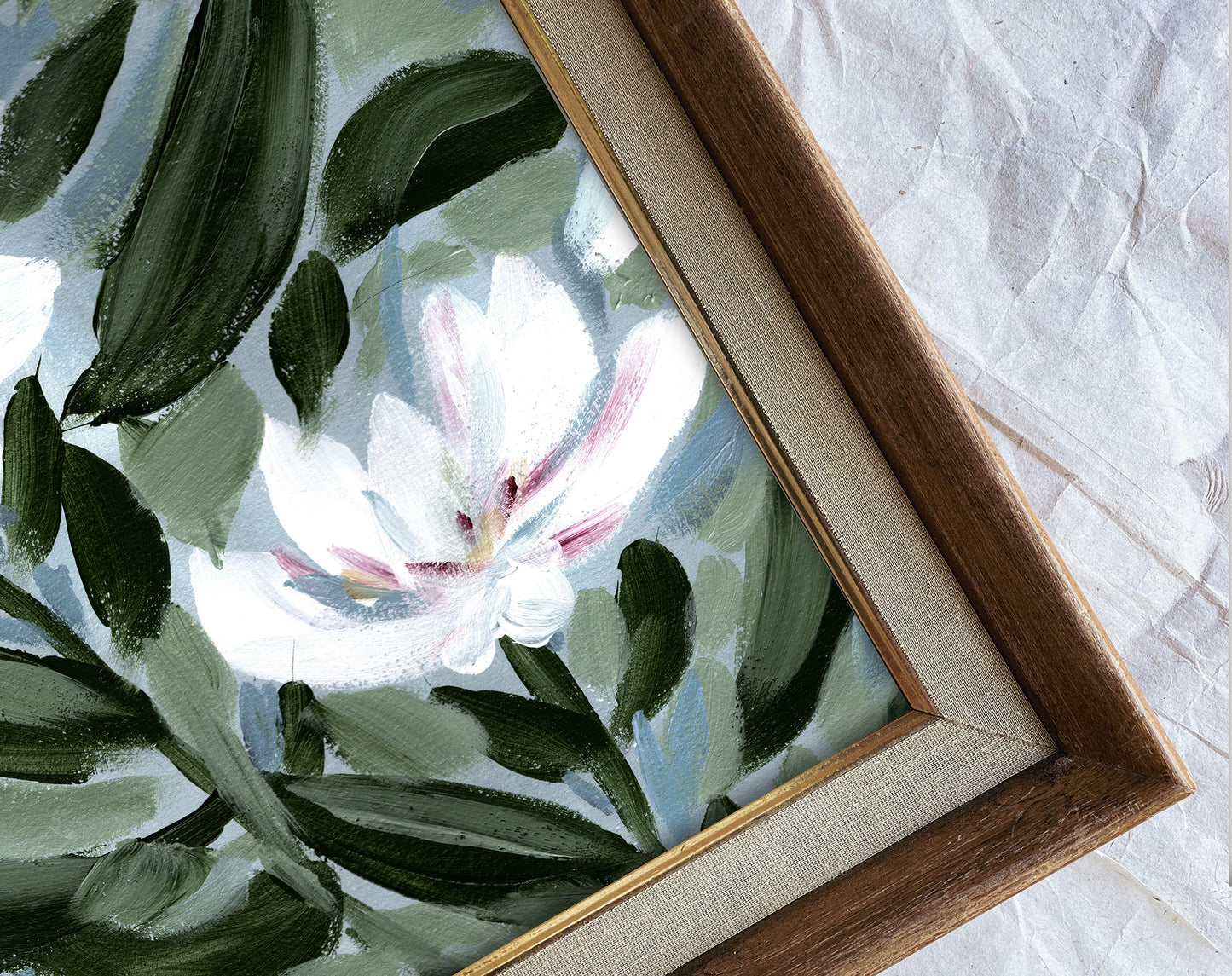 Framed artwork of a floral design with green leaves and a white flower on a textured surface.