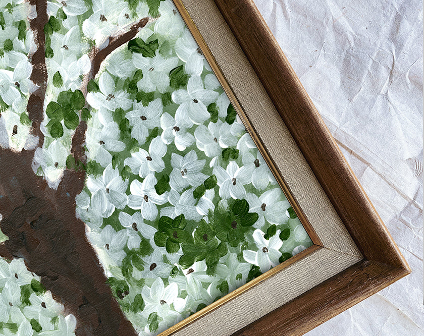 Framed artwork of a tree with white flowers and green leaves on a textured surface