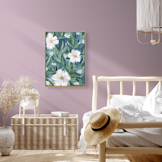 Floral artwork on a purple wall above a bed with a straw hat and wicker basket.
