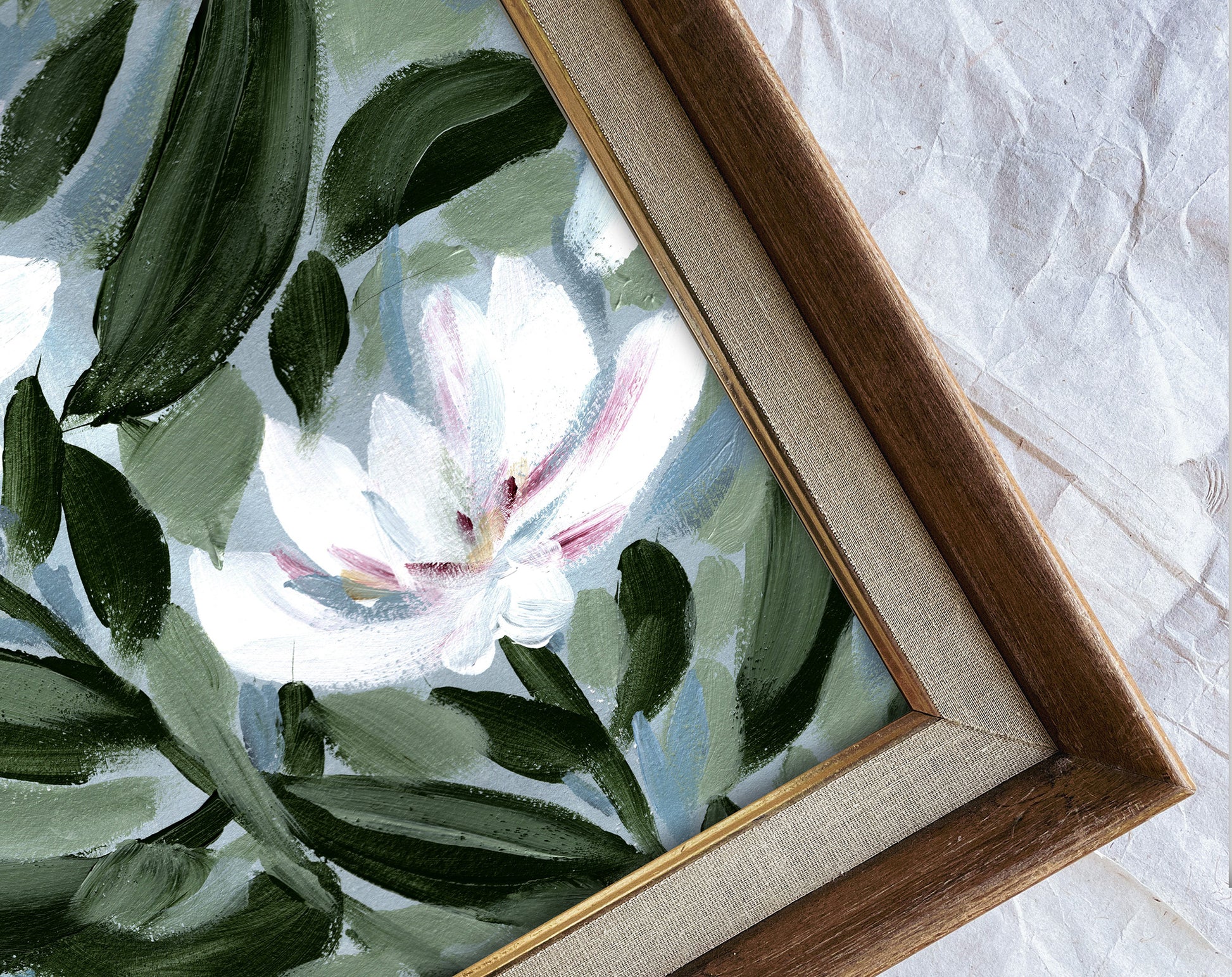 Framed artwork of a floral design with green leaves and a white flower on a textured surface.