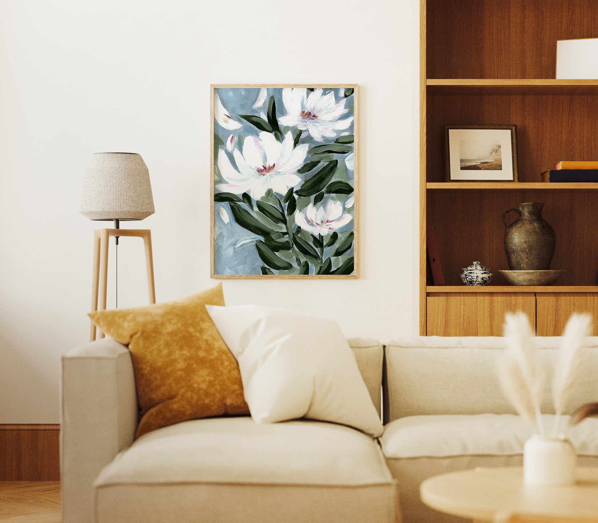 Living room with a beige sofa, floral artwork on the wall, and wooden shelves.