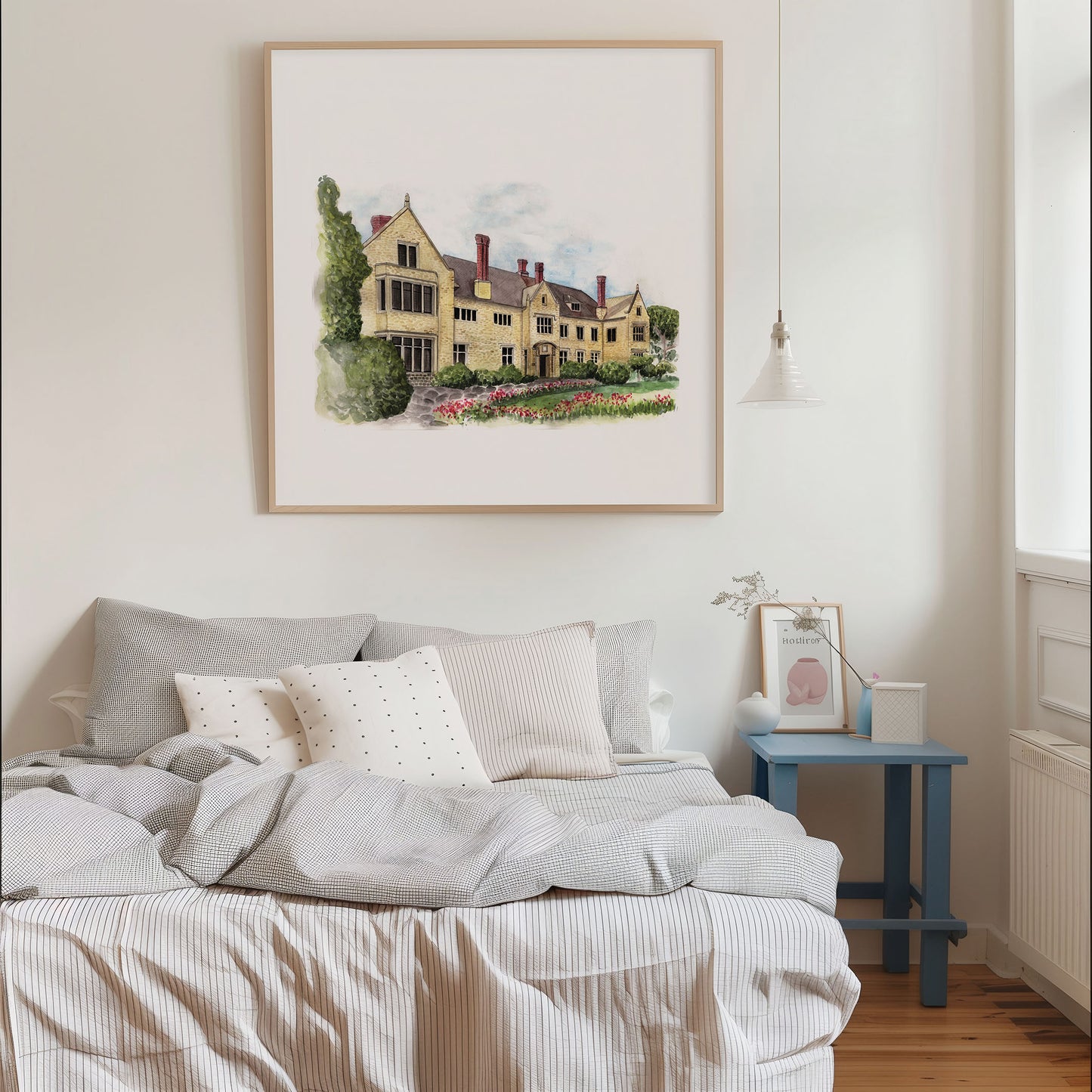 Bedroom with a bed, framed artwork of a house, and a side table.