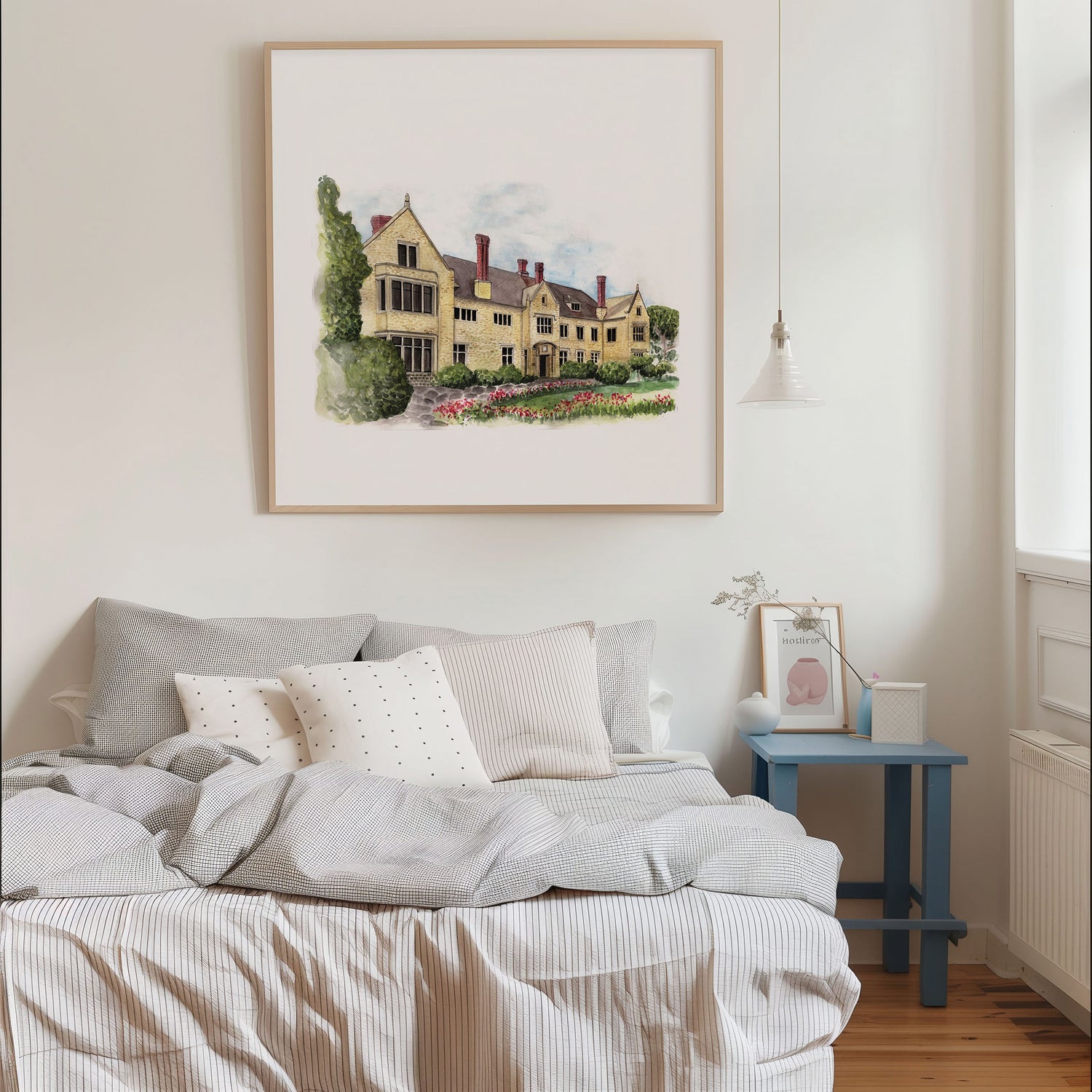 Bedroom with a bed, framed artwork of a house, and a side table.