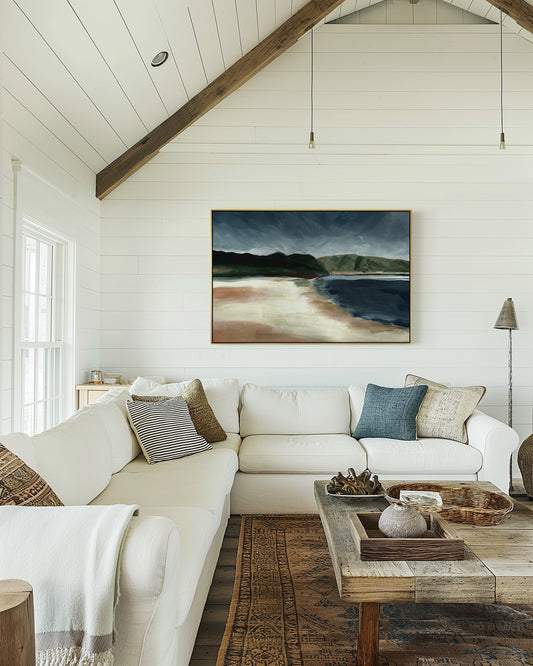 Living room with a white sofa, wooden coffee table, and a painting of a landscape on the wall.