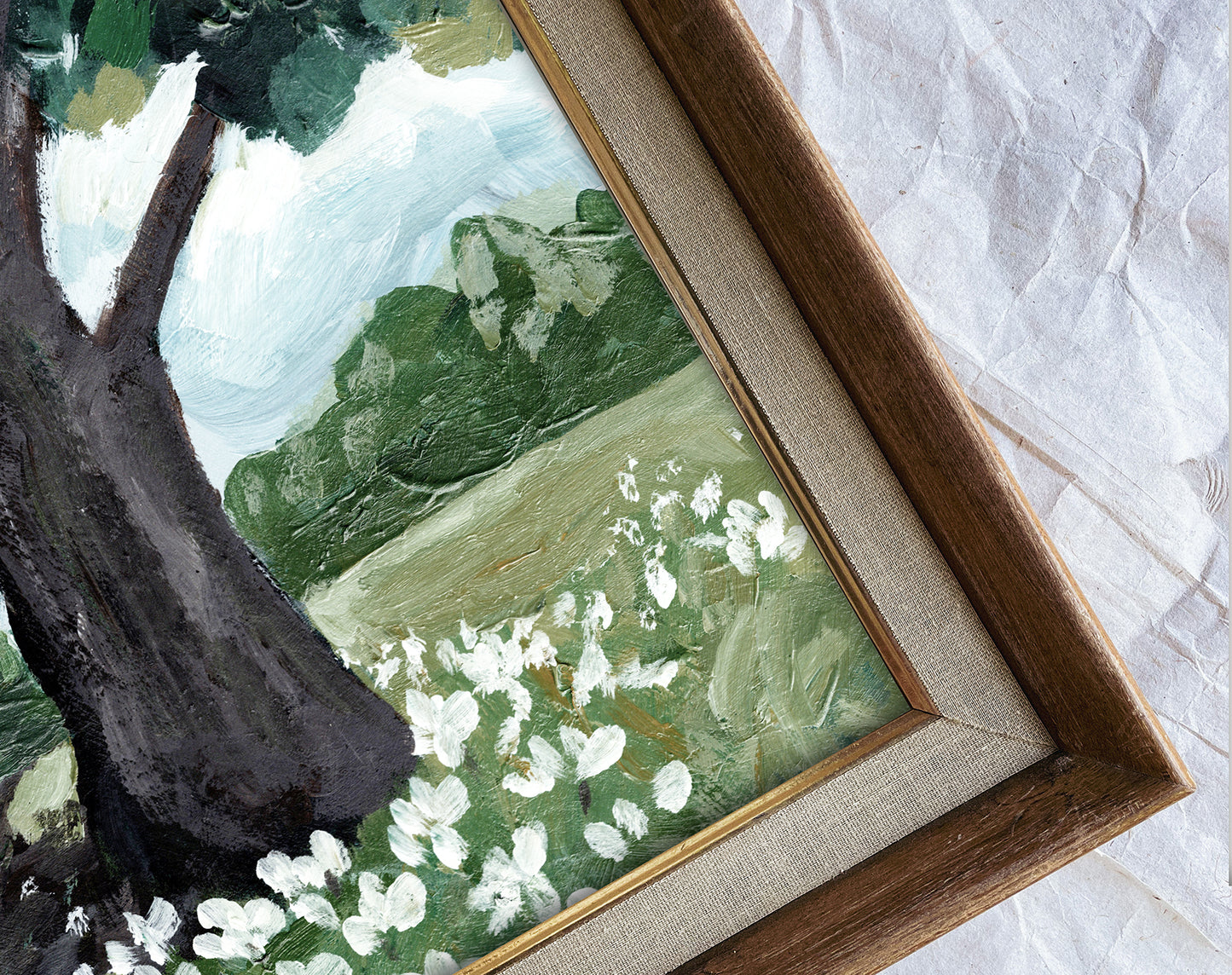 Framed painting of a natural landscape with trees and flowers on a textured white surface.